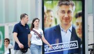 People pass a campaign poster of Chief of the conservative HDZ party Andrej Plenkovic waves in Zagreb on September 8, 2016. Croatians will choose between two career diplomats for their next prime minister on September 11's early election, which follows mo