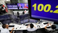 Employees of a foreign exchange trading company work near monitors displaying first US presidential debate between US Republican nominee Donald Trump and Democratic presidential nominee Hillary Clinton (top C), and the Japanese yen's exchange rate against