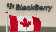 A Blackberry logo hangs behind a Canadian flag at their offices on the day of their annual general meeting for shareholders in Waterloo, Canada June 23, 2015. REUTERS/Mark Blinch/File Photo
