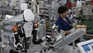 A humanoid robot works side by side with employees in the assembly line at a factory of Glory Ltd., a manufacturer of automatic change dispensers, in Kazo, north of Tokyo, Japan. REUTERS/Issei Kato