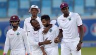 West Indies spinner Devendra Bishoo (2R) celebrates with his teammates after taking the wicket of Pakistani batsman Asad Shafiq on the fourth day of the first day-night Test between Pakistan and the West Indies at the Dubai International Cricket Stadium i