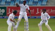 West Indies' captain Jason Holder (C) and wicketkeeper Shai Hope (R) celebrate after bowling out Pakistani batsman Mohammad Nawaz (L) on the fourth day of the first day-night Test between Pakistan and the West Indies at the Dubai International Cricket Sta