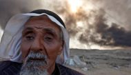 A man returns to his village after it was liberated from Islamic State militants, south of Mosul in Qayyara, Iraq, October 22, 2016. The fumes in the background are from oil wells that were set ablaze by Islamic State militants. REUTERS/Alaa Al-Marjani