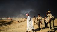 A displaced Iraqi man walks past security forces at a refugee camp on October 22, 2016 in the town of Qayyarah, south of Mosul, as an operation to recapture the city of Mosul from the Islamic State group takes place. Iraqi security forces battled for a se
