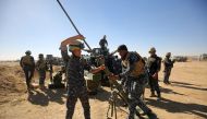 Iraqi policemen clean a weapon yesterday as 30,000 pro-government troops prepare to launch an attack on Mosul in Iraq. Iraq assembles its troops ahead of Mosul offensive against ISIS. / AFP.