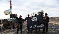 Iraqi soldiers pose with an Islamic State (IS) group flag as they hold a position in the village of Gogjali, a few hundred metres of Mosul's eastern edge, on November 2, 2016, as clashes go on between Iraqi army forces and the jihadists to retake Mosul, t