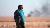 A Syrian Democratic Forces (SDF) fighter stands near rising smoke, north of Raqqa city, Syria November 6, 2016. REUTERS/Rodi Said
