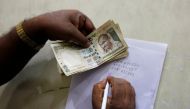 A man writes the serial numbers of 500 Indian rupee banknotes on the back of a form before depositing them in a bank in Kolkata, India, November 13, 2016. REUTERS/Rupak De Chowdhuri
