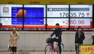 Pedestrians stand in front of an electric quotation board displaying the Nikkei key index of the Tokyo Stock Exchange (TSE) in Tokyo on November 14, 2016. AFP / KAZUHIRO NOGI

