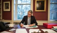 British Chancellor of the Exchequer Philip Hammond is pictured sitting at his desk, with a copy of his Autumn Statement, in his office at 11 Downing Street in central London on Nov. 22, 2016. / AFP / POOL / Stefan Rousseau