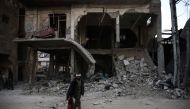  An injured Syrian man walks with his son past a destroyed building on November 22, 2016, in the rebel-held town of Douma, on the eastern outskirts of the capital Damascus. / AFP / Sameer Al-Doumy