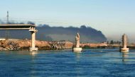 A bridge destroyed by Islamic State (IS) group is seen in front of black plumes of smoke from burning oil wells, set ablaze by retreating militants, in Qayyarah, some 60km south of Mosul, Iraq, yesterday.