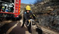 An Israeli firefighter unloads hose as they battle a fire in the village of Nataf close to Jerusalem, as it continues to spread in the area, on November 26, 2016. Wildfires near Jewish settlements in the occupied West Bank have forced hundreds to flee the