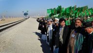 Officials and Turkmen traditional dancers gather at Turkmenistan's Imamnazar customs point on November 28, 2016 as they watch a freight train heading to Afghanistan's Akina during a ceremony marking the opening of the first section of a $2 billion railway