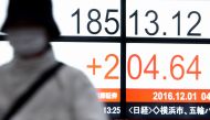 A woman walks past an electric quotation board displaying the Nikkei key index of the Tokyo Stock Exchange (TSE) in front of a securities company in Tokyo on December 1, 2016. Tokyo's benchmark stock index on December 1 jumped to its best close this year,