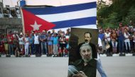 A man carries a picture showing Cuba's former President Fidel Castro and Jose Marti, the 19th century hero of Cuban independance, as people line the street while waiting for the ashes of Castro to pass during a journey to the eastern city of Santiago de C