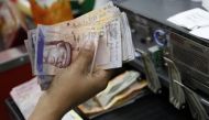 A cashier counts Venezuelan bolivar notes in a state-run supermarket in Caracas January 9, 2015. REUTERS/Carlos Garcia Rawlins