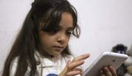 Syrian Bana al-Abed, who with the help of her mother had been posting heartrending tweets in English on life in the besieged eastern districts of Syria's Aleppo, uses a smart-phone to check her Twitter account in her home in east Aleppo, on October 12, 20