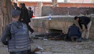 Egyptian security forces check a body at the site of a bomb attack next to a police checkpoint in the western Talibiya district of the capital Cairo on December 9, 2016. AFP