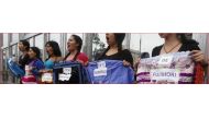 Women, with their bodies painted with blood, hold signs reading: 