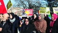 Protesters hold placards reading 