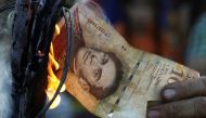 A man burns a 100-bolivar bill during a protest in El Pinal, Venezuela December 16, 2016. REUTERS/Carlos Eduardo Ramirez
