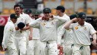 Australia's captain Steve Smith (C) adjusts his collar as he walks off the field with teammates after beating Pakistan in the first day-night cricket Test match between Australia and Pakistan in Brisbane on December 19, 2016. (AFP / Saeed KHAN)