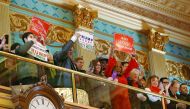 Supporters of President-elect Donald Trump hold signs in the Senate gallery in Lansing, Michigan.