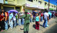 A Venezuelan soldier controls the crowd as people queue to buy goods from a food wholesaler in Ciudad Bolivar, yesterday.