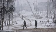 Syrian pro-government forces walk as snow falls in Aleppo on December 21, 2016.    AFP / GEORGE OURFALIAN
