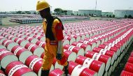 A worker walks over the barrels of crude oil at an inventory facility.