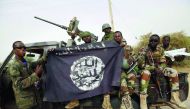 Nigerien soldiers hold up a Boko Haram flag they seized in the recently retaken town of Damasak, Nigeria.