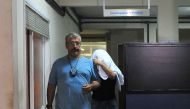 A Brazilian civil policeman escorts the wife of Greece's ambassador to Brazil Kyriakos Amiridis, Francoise de Souza Oliveira, who murdered him in a plot hatched with her police officer lover, who confessed to the crime, on December 30, 2016 in Rio de Jane