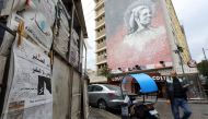 A man walks past a newspaper stand, displaying the As-Safir newspaper, in Beirut's Hamra neighborhood on December 31, 2016. The Arabic political daily newspaper based in Beirut, As-Safir meaning 'The Ambassador', was founded in March of 1974 and had been 