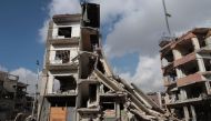 Syrians walk past a destroyed building in the rebel-held town of Douma, on the eastern outskirts of Damascus, on December 30, 2016, on the first day of a nationwide truce. AFP / Abd Doumany
