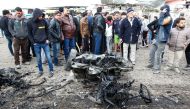 Iraqis inspect a charred vehicle on the site of a bomb attack in Sadr City, a majority Shiite neighbourhood in the northeast of the capital Baghdad, on January 2, 2017.  AFP / SABAH ARAR
