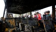 People look at a burned vehicle at the site of car bomb attack in a busy square at Baghdad's sprawling Sadr City district, in Iraq January 2, 2017. REUTERS/Ahmed Saad.