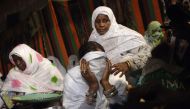 Algerian women help a bride cover her face during a group wedding ceremony, organised by a charity for economically disadvantaged people and orphans, in the Sahara desert village of In-Salah, south Algeria, on December 21, 2016.