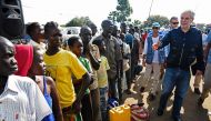 EU Commissioner for Humanitarian and Crisis Management Christos Stylianides speaks with newly arrived refugees from South Sudan to Uganda (AFP / ISAAC KASAMANI) 