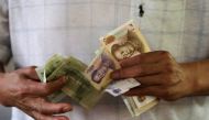  A customer counts Chinese Yuan notes at a market in Beijing, August 12, 2015. REUTERS/Jason Lee/File Photo