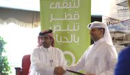 Engineer Abdul Aziz Ahmed Al Hammadi (left), Conservation and Energy Efficiency Department Manager at Kahramaa, and Engineer Saadi Al Said, Director for Administration and Planning at Qatar National Library, exchanging documents.