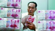 A Chinese bank staff member counting stacks of 100-yuan notes at a bank in Huaibei, east China’s Anhui province.