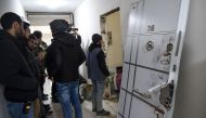 Turkish plain clothes police officers wait next to a damaged door at the apertment where the main suspect in the Reina nightclub rampage was arrested by Turkish police the night before, in Istanbul on January 17, 2017.  AFP / OZAN KOSE