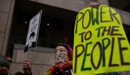 A woman protesting the inauguration of Donald Trump holds signs before the start of the Presidential Inauguration of Trump near Freedom Plaza on January 20, 2017 in Washington, DC. Trump will become the 45th President of the United States after a swearing