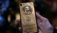 An employee of Caviar Phones, a Russian-Italian company specializing in smartphone customization displays a special gold-plated iPhone 7 smartphone bearing the likeness of  Trump (AFP) 