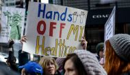 A woman holds a sign reading 