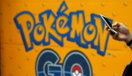 A man uses a mobile phone in front of an advertisement board bearing the image of Pokemon Go at an electronic shop in Tokyo, Japan. Reuters/Kim Kyung-Hoon/File Photo
