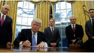 US President Donald Trump, watched by (L-R) Vice President Mike Pence, White House Chief of Staff Reince Priebus, head of the White House Trade Council Peter Navarro and senior advisor Jared Kushner, in the Oval Office of the White House in Washington Jan