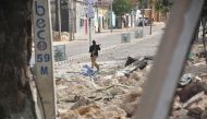 A Somalian policeman holds a weapon following an attack outside an hotel on January 25, 2017, in Mogadishu. Many people were killed after two car bombs exploded outside a popular Mogadishu hotel and gunmen forced their way inside the building and opened f
