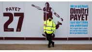 (FILES) This file photo taken on January 14, 2017 shows a security guard standing beside the club mural praising West Ham United's French midfielder Dimitri Payet ahead of the English Premier League football match between West Ham United and Crystal Palac